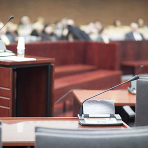 A courtroom with rows of chairs and microphones.