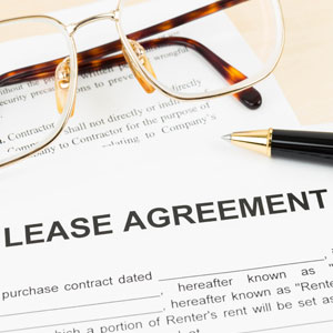 Black lease agreement with pen and glasses - Manavi Law Group, APLC.